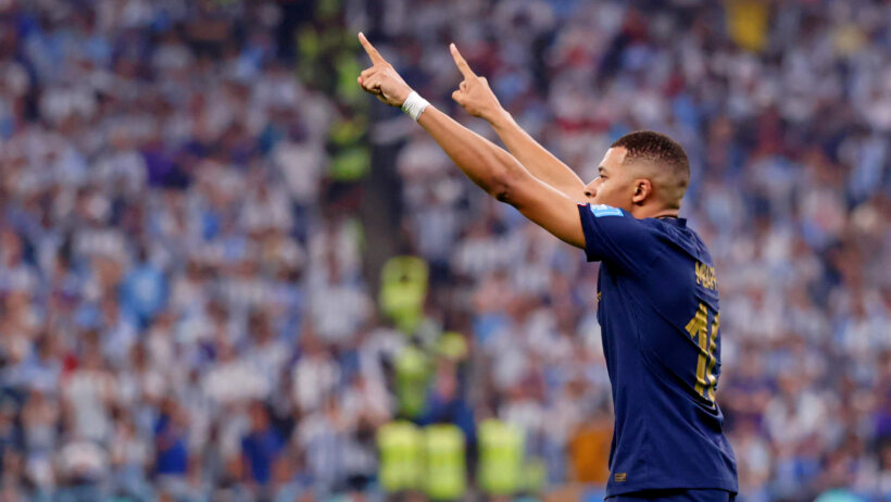 French soccer player Kylian Mbappe with raised hands, pointing in the air.