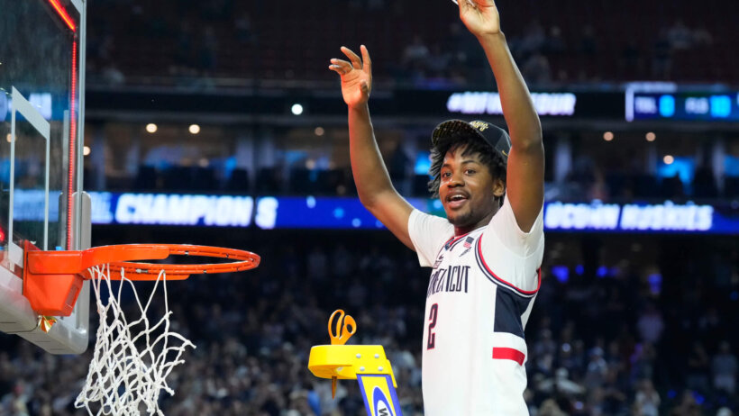 Connecticut Huskies guard Tristen Newton cutting down the nets after winning the national championship