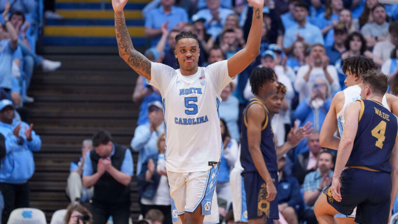 UNC Tar Heels college basketball player raising hands white jersey