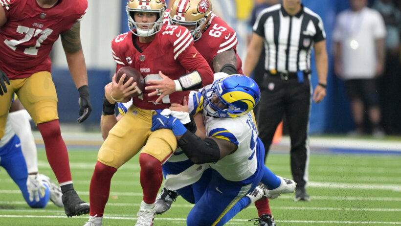 San Francisco 49ers quarterback Brock Purdy getting tackled by Los Angeles Rams defensive tackle Kobie Turner