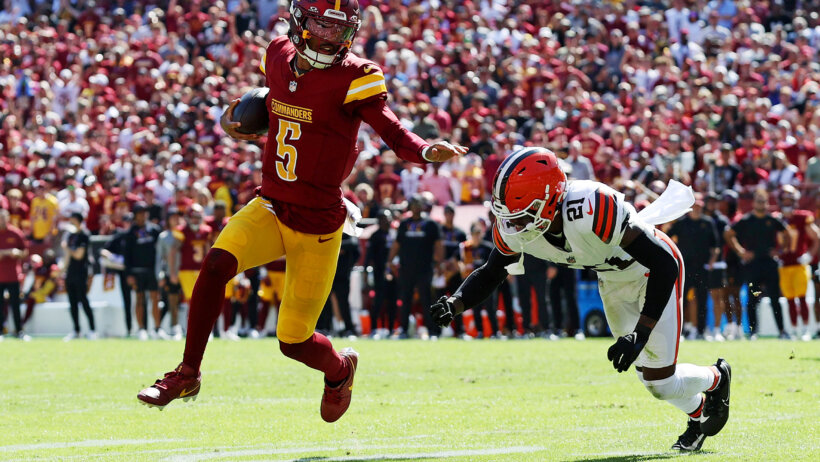 A Cleveland Browns player attempts to tackle Washington Commanders player Jayden Daniels while running with a football,