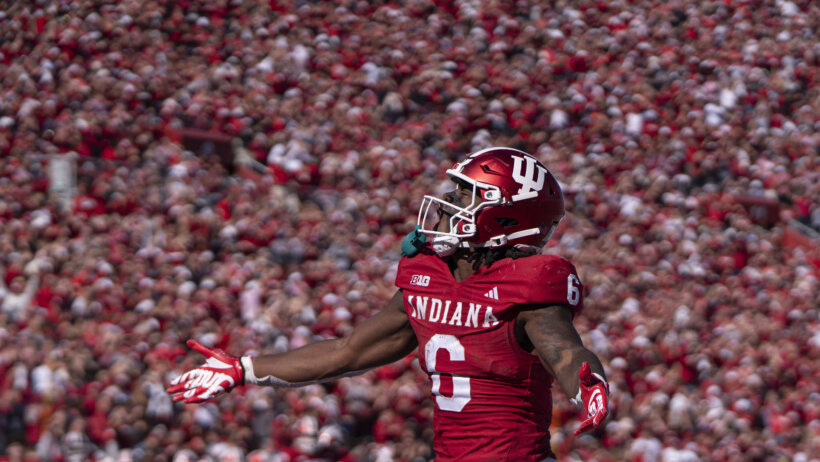 An Indiana Hoosiers football player celebrates in front of packed stadium of fans.