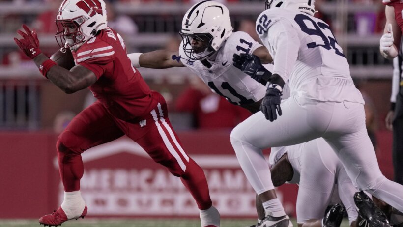 Penn State football players chasing a Wisconsin running back.