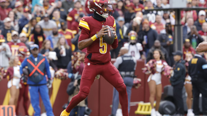 Washington Commanders football player Jayden Daniels holding a football.