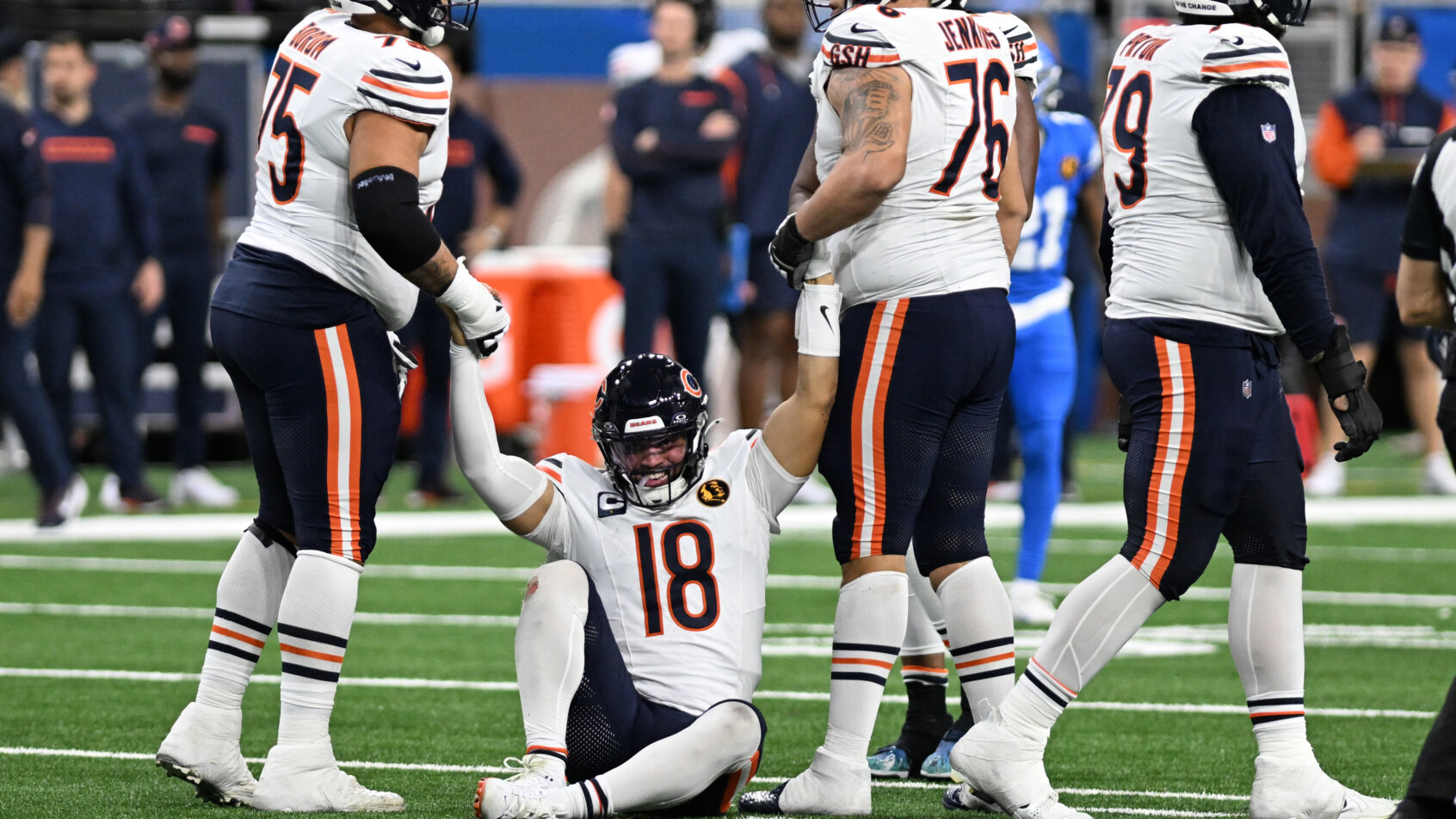 Caleb Williams being helped up by his offensive linemen