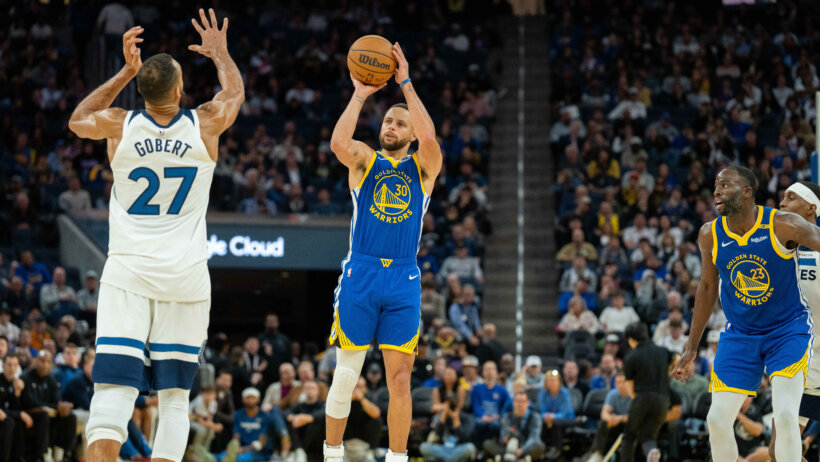 Golden State Warriors guard Stephen Curry shooting a three as Minnesota Timberwolves center Rudy Gobert tries to close out