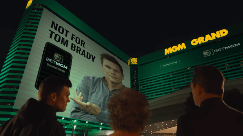 Tom Brady Vince Vaughn looking at poster side of MGM Grand building