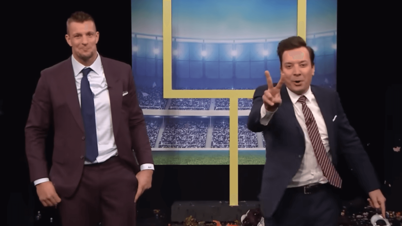 Rob Gronkowski and Jimmy Fallon holding up two fingers in suits